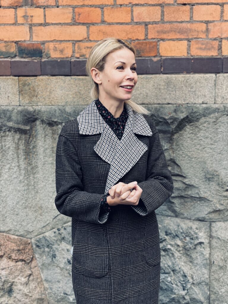 Anna König Jerlmyr standing next to red brick building.