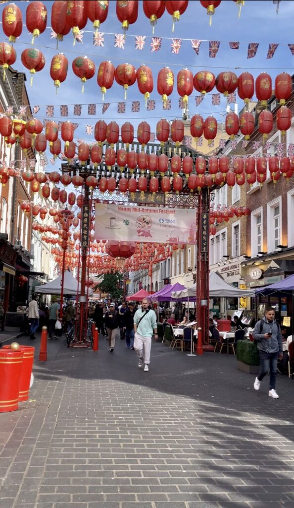 Street in Chinatown, London with red ornamental lights hanging above.