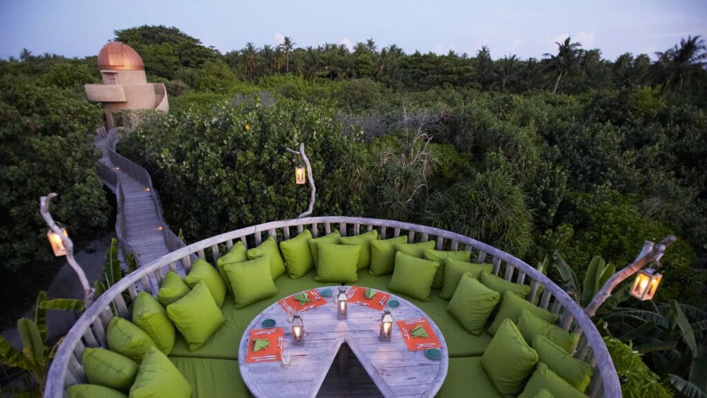Round outdoor dining with trees and bushes in the background.  Soneva Fushi, Maldives.