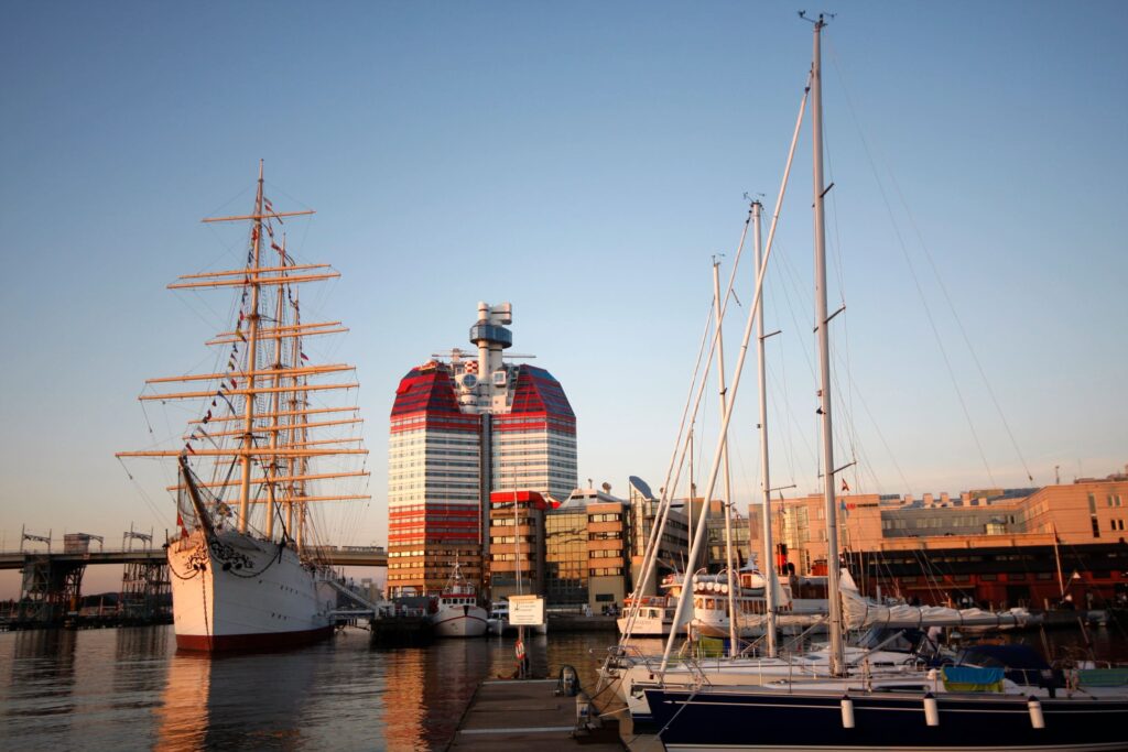 An old classic ship in a harbour with a high-rise in the background