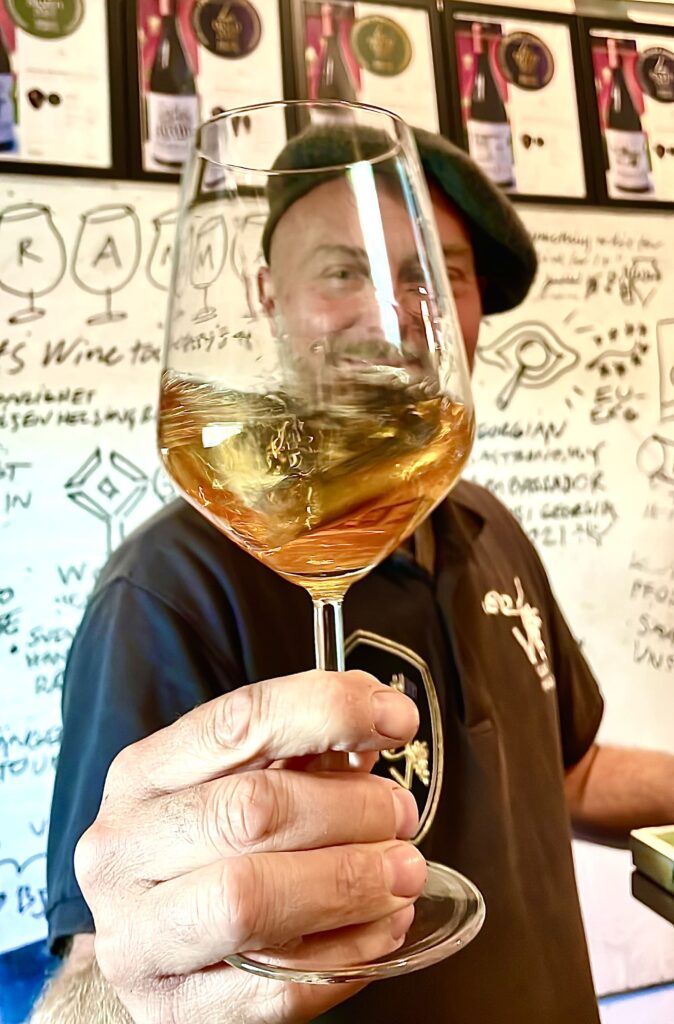 A man swirls a glass of orange wine.