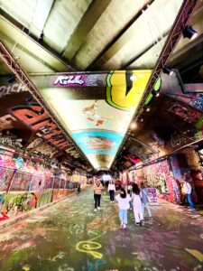 Vaulted tunnel with graffiti covering floor, walls, and roof