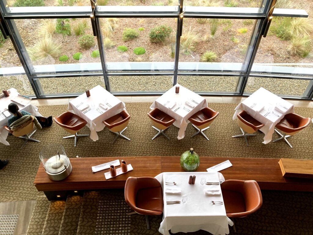 View of restaurant tables from above with bushy landscape view from the windows