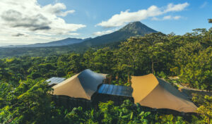 Tented camp with green forest and mountains as a backdrop
