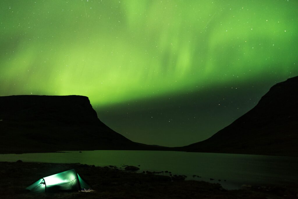 Northern Lights in intense-green light display among mountains