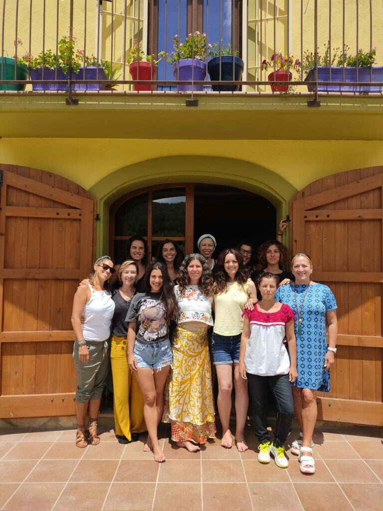 Group of women posing for a photograph outside a yellow house