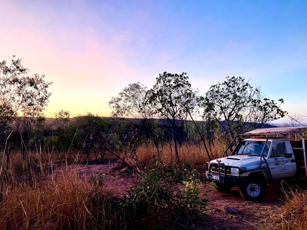 Sunset in the bush with a off-road vehicle parked by the side