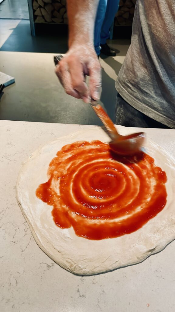 Tomato sauce spread out on pizza bottom