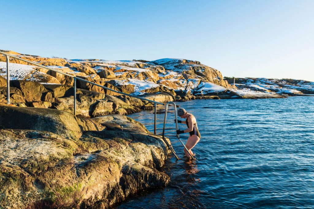 Woman getting climbing down to swim in the winter sea