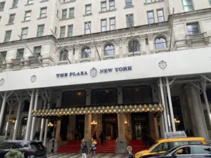 Main entrance of The Plaza Hotel, New York with people and cars outside.