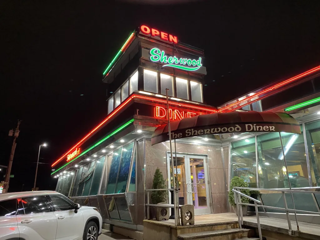 Red and green neon lights on the glass facade of a diner. 