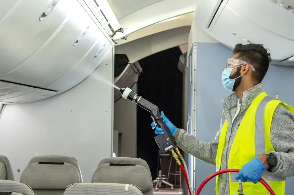 Man in mask spraying inside of airplane. 