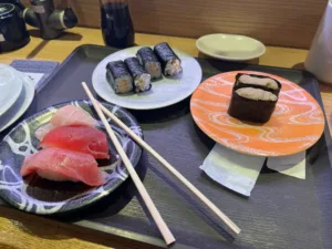 3 plates of sushi with chopsticks.