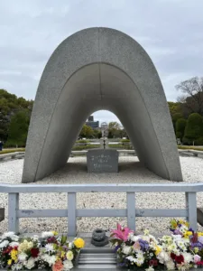 Reverse U-shaped stone memorial with flowers.