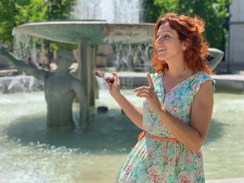 Woman standing in front of a fountain wearing a flowery dress.