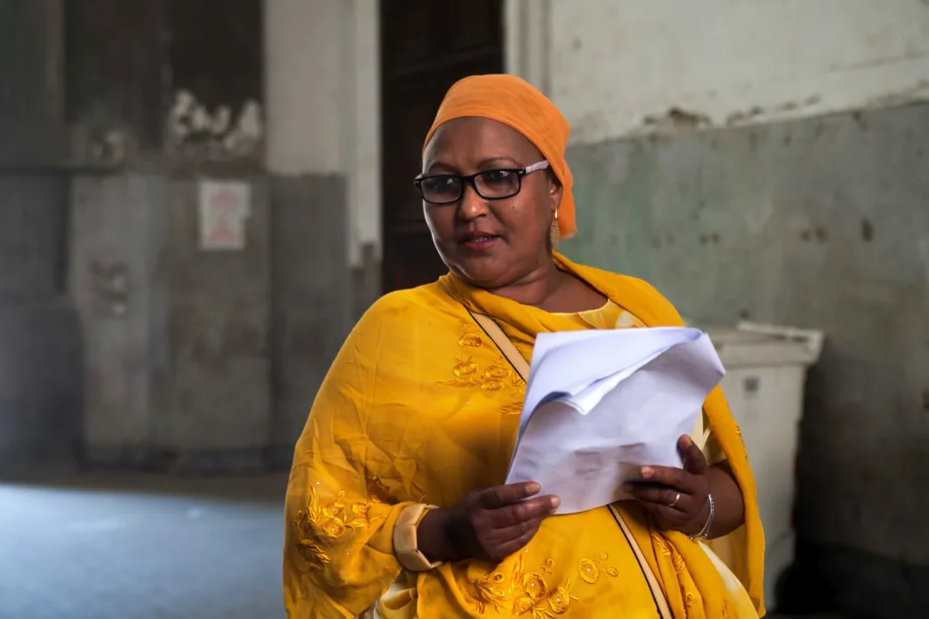 Woman in yellow dress with a pages of paper in her hands.
