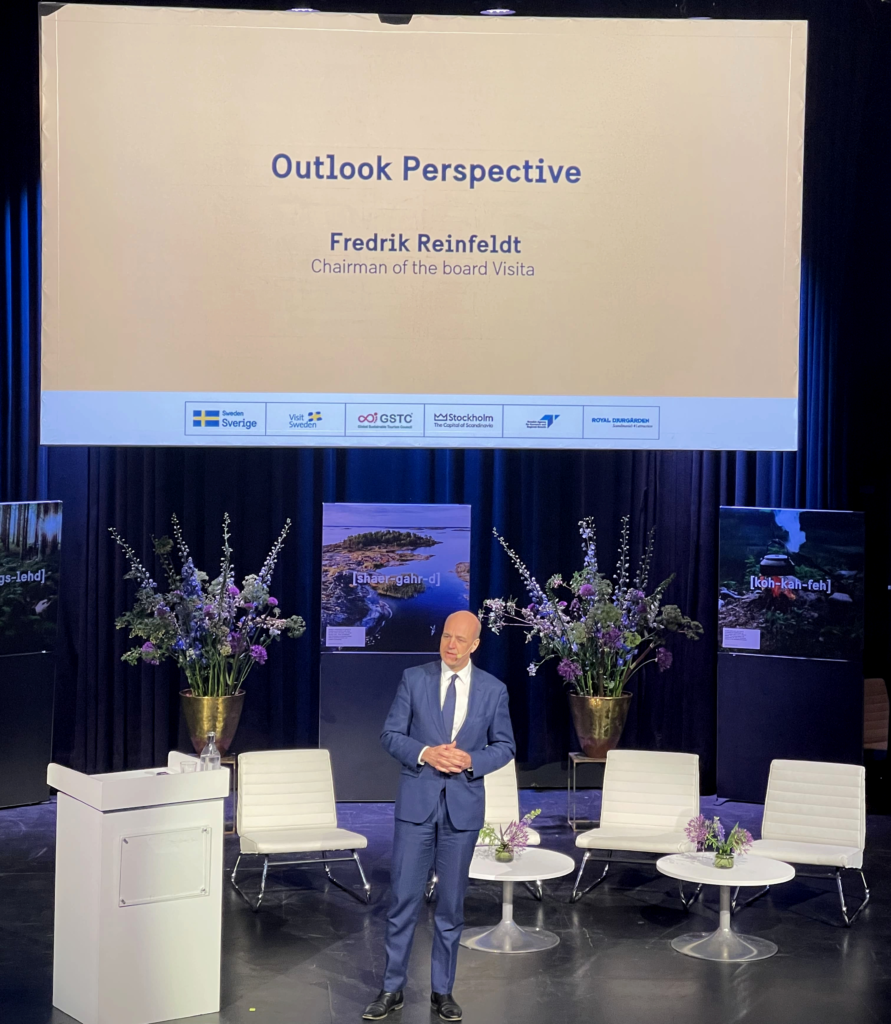  Fredrik Reinfeldt on stage presenting about travel and tourism.