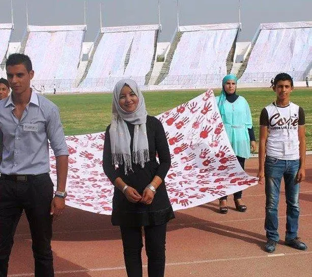 Woman standing inside a stadium with a couple of people around her.