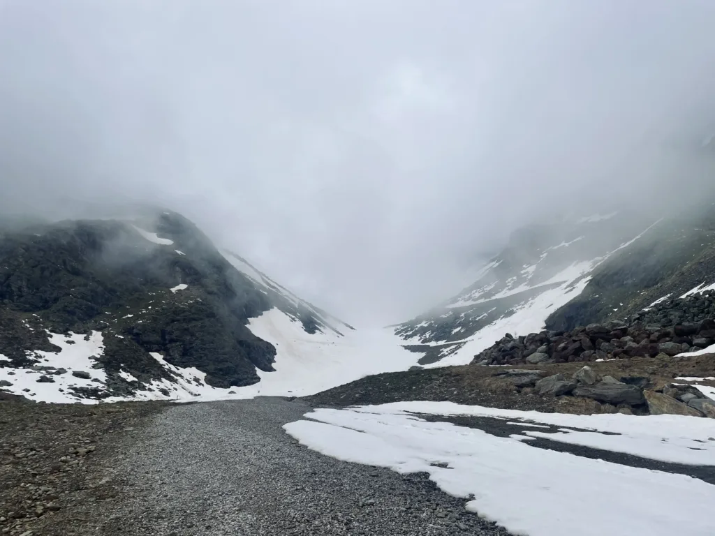 A glacier flanked by mountains in foggy conditions.