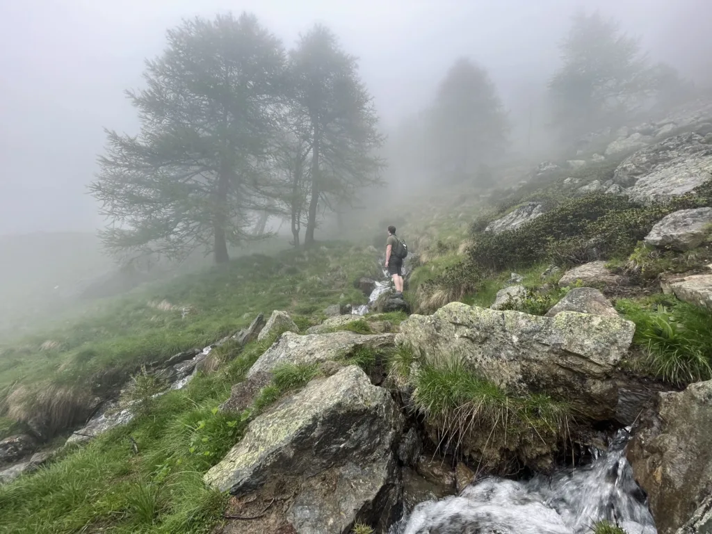 Man standing on rocks on on a hiking path covered in fog.