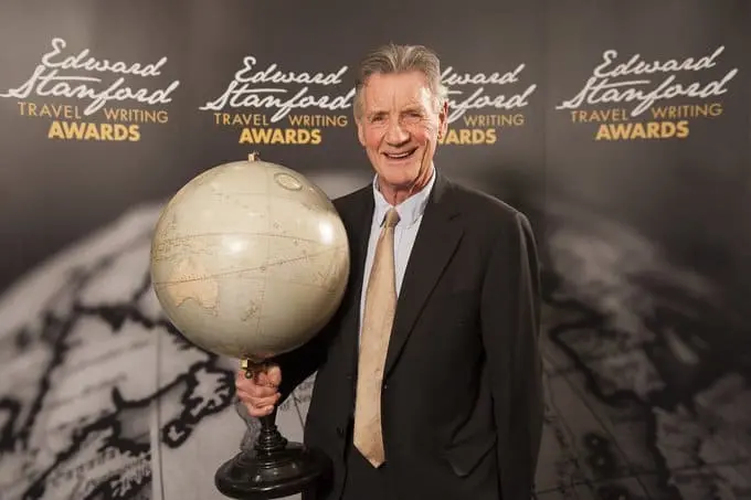 Man holding a globe in front of a poster for a travel award