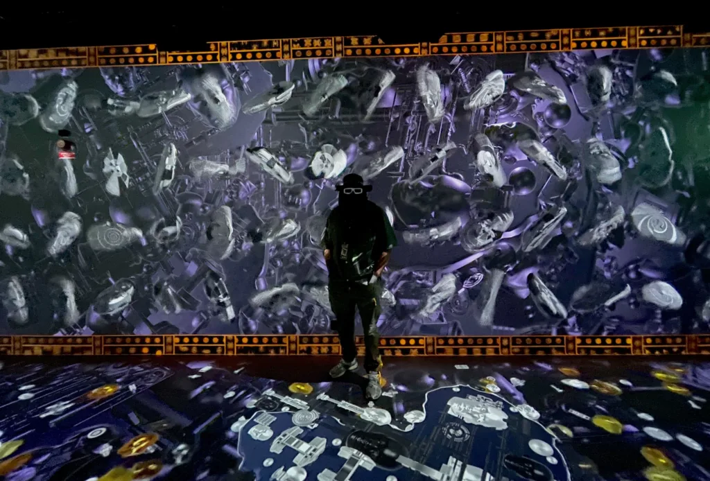 Man in mask posing near a wall of projected art