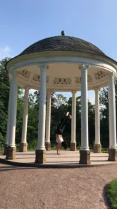 Person doing handstand inside of a garden temple.