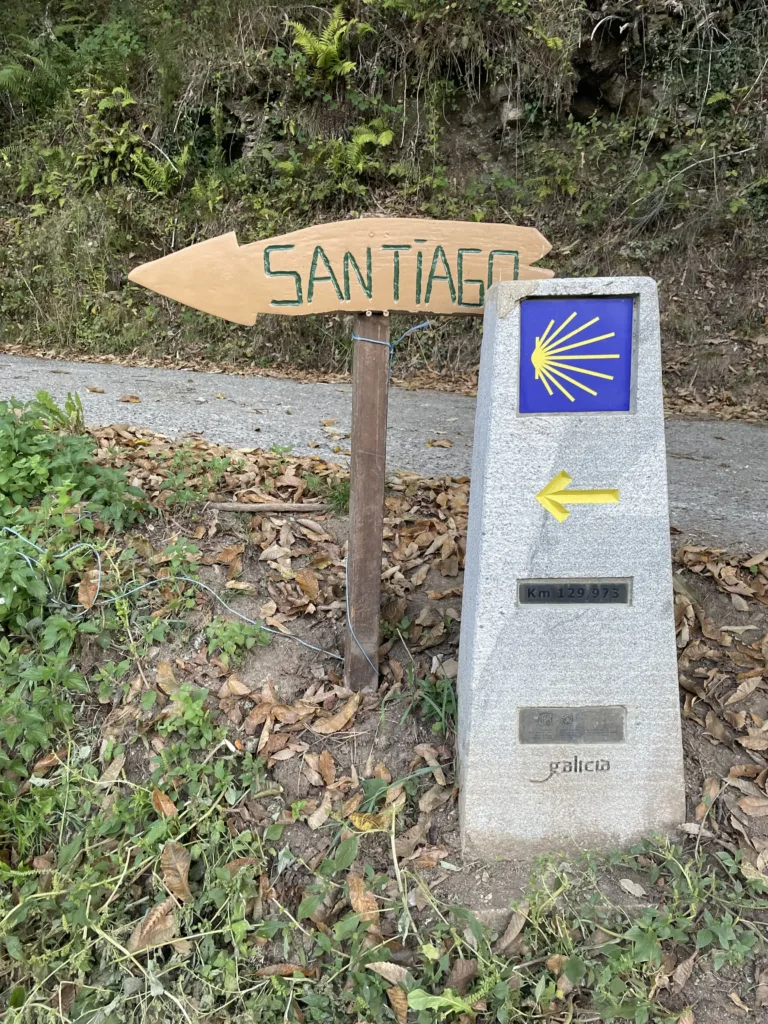 Trail marker reading Santiago next to a yellow arrow