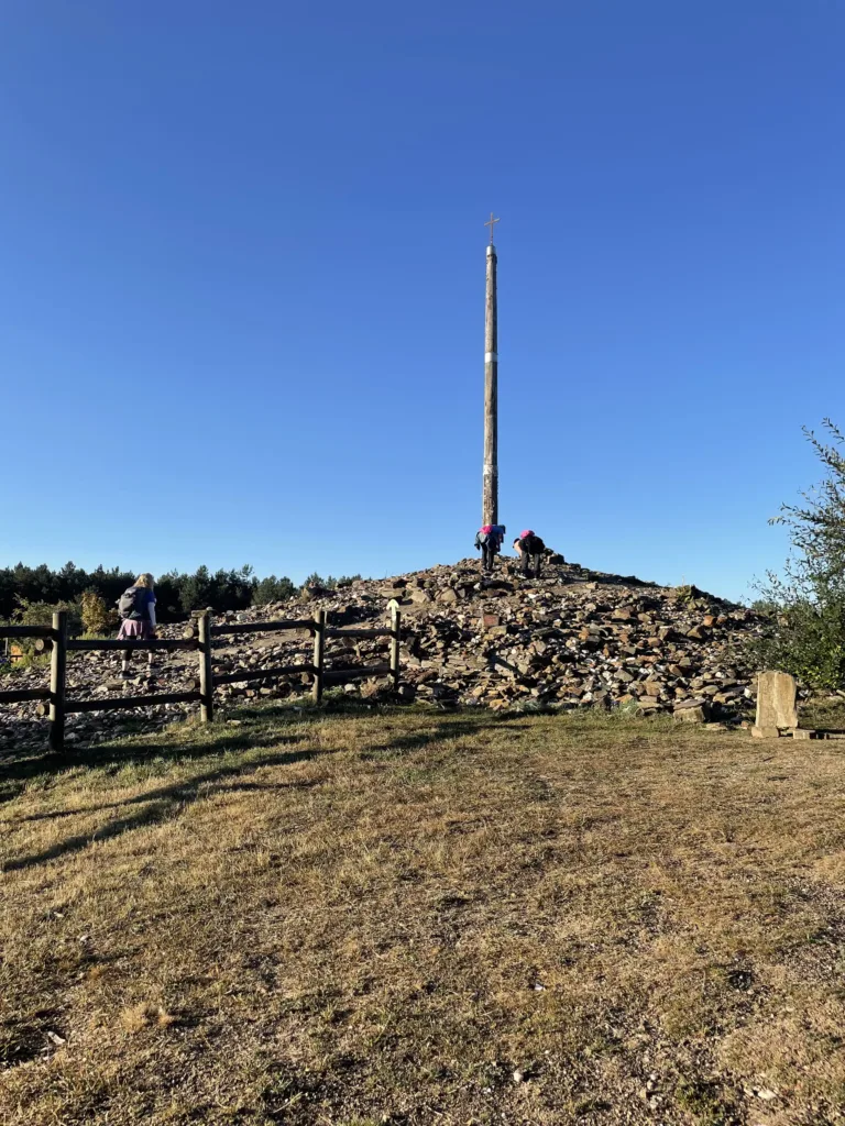 A pillar with a cross on top situated on a raised platform of rocks.