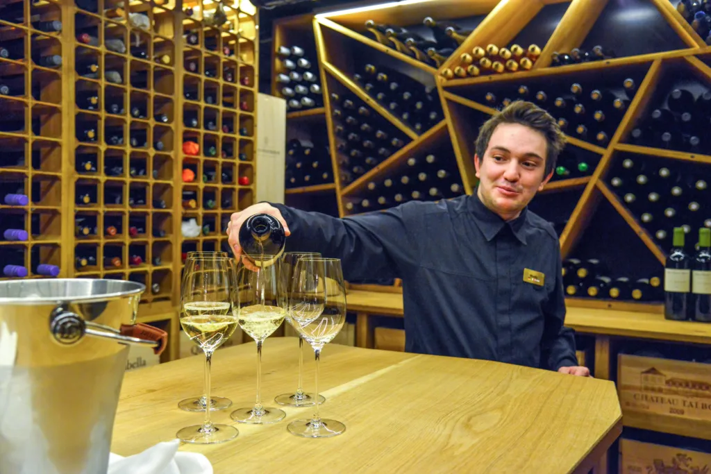 Man pouring wine in glasses on table