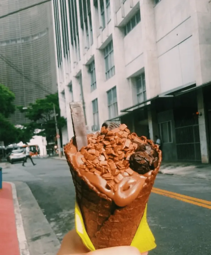 Person holding an ice cream cone in an urban landscape