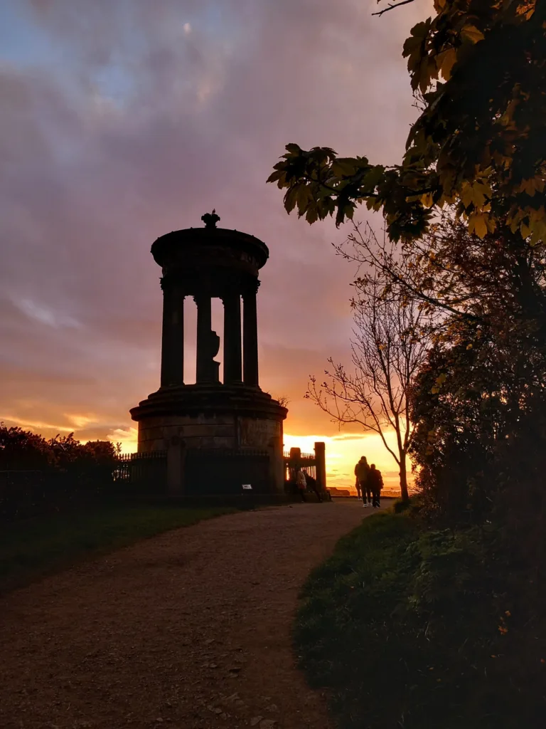 Monument seen during sunset with two people walking next to it.