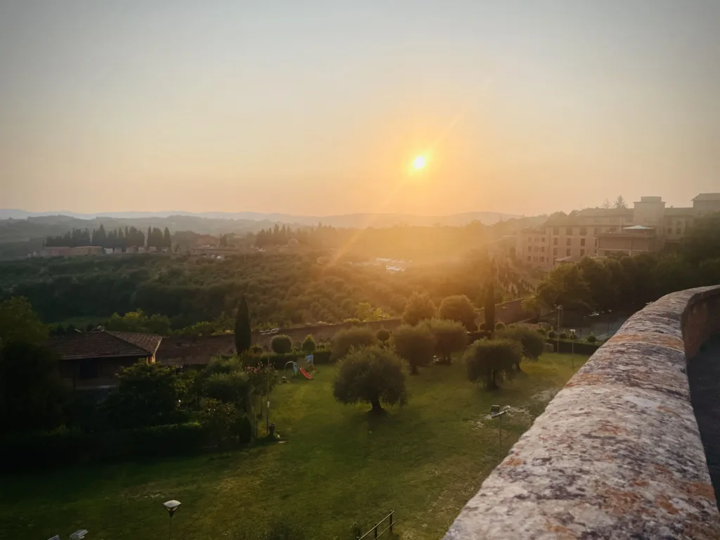 Sun over hilly landscape seen from a wall