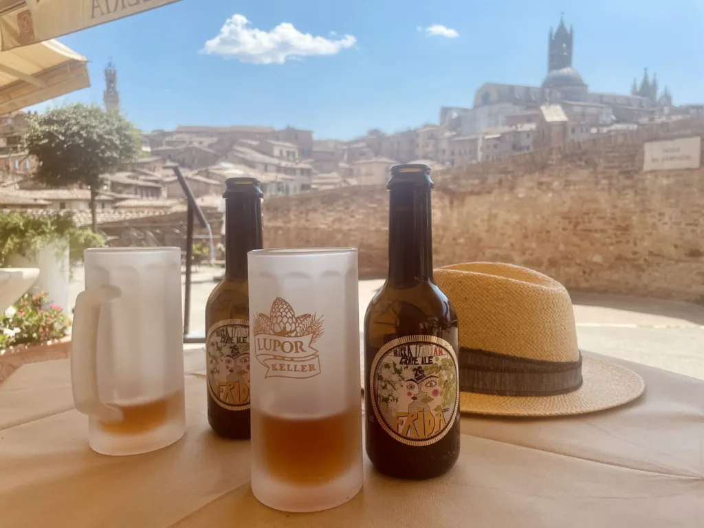 Two beer bottle and two glasses with view of a wall and city