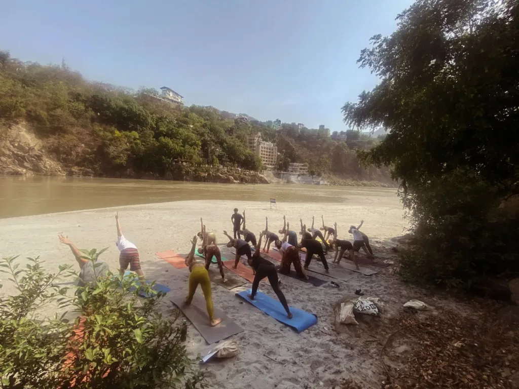 Group of people practising yoga by a river