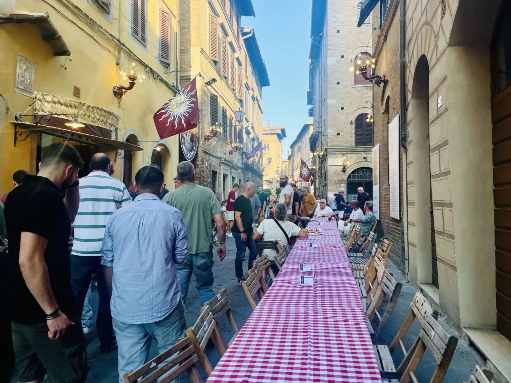 Long table on narrow street with people gathering for a feast