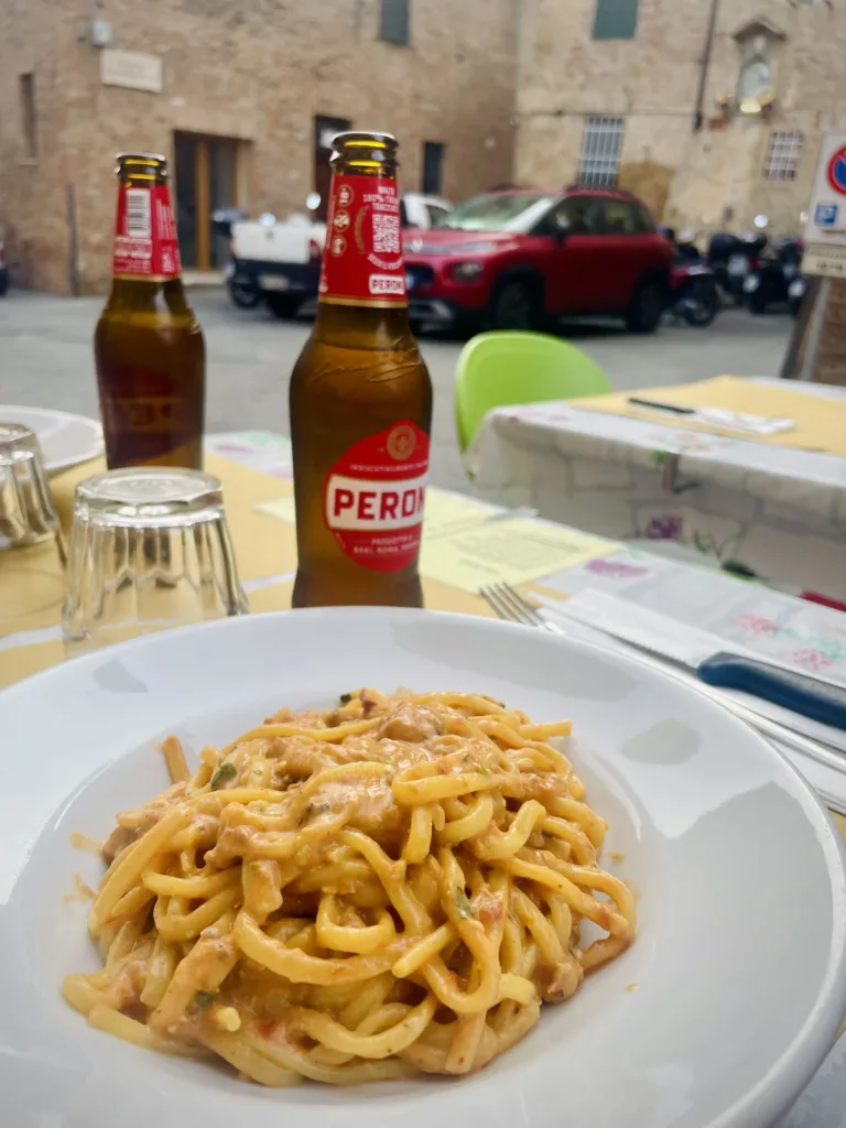 Plate of pasta with two beers in outside seating restaurant