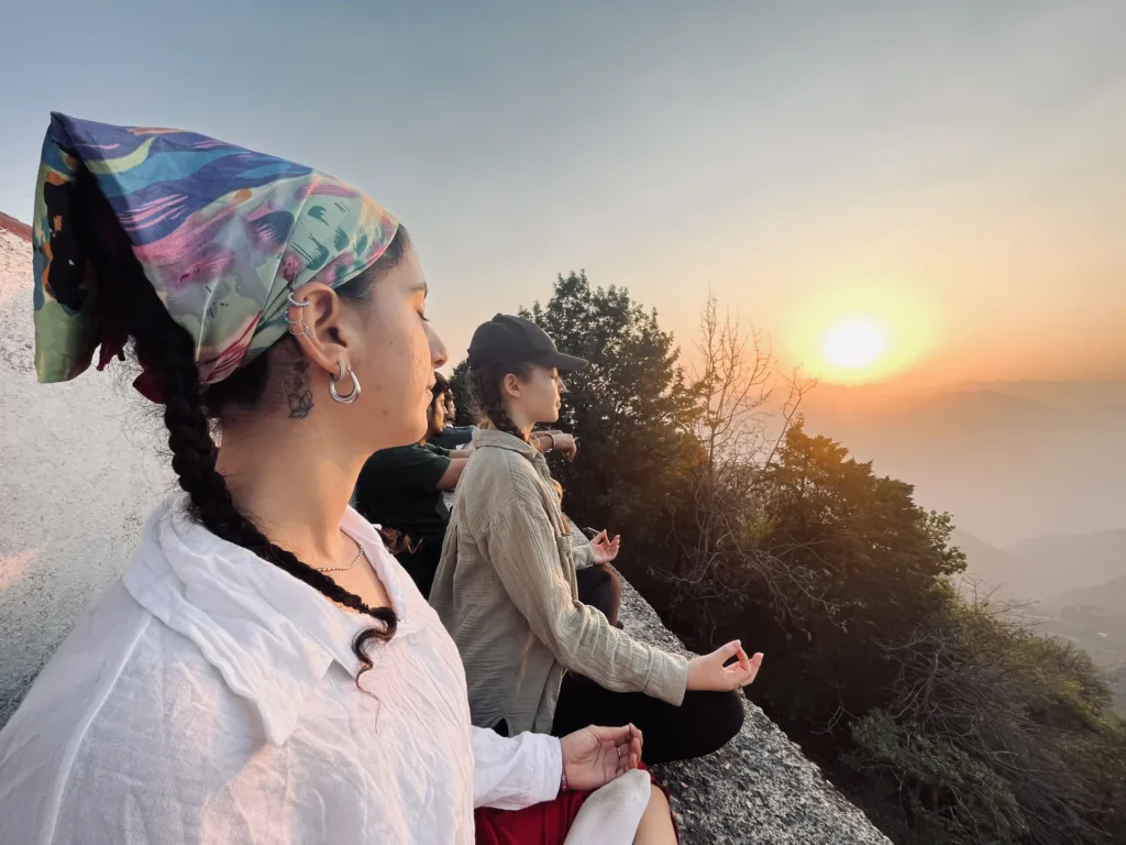 Women meditating at sunrise in mountainous setting