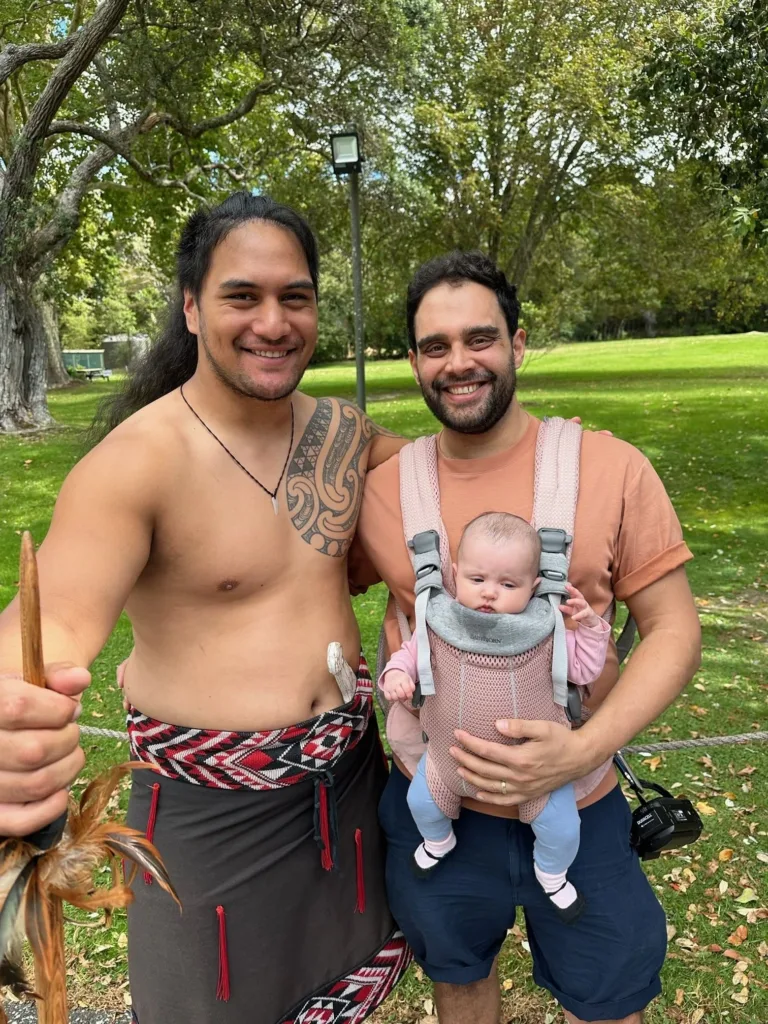 Man with tattoo over chest and another man carrying a small child