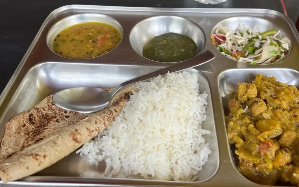 A tray with small servings of rice, bread, salad, and sauces.