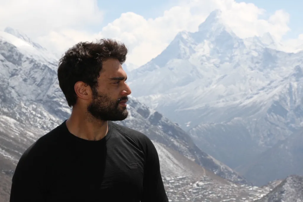 Man posing in front of snow capped mountains