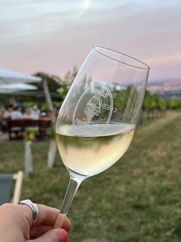 Hand holding a glass of white wine at an angle to judge the colour