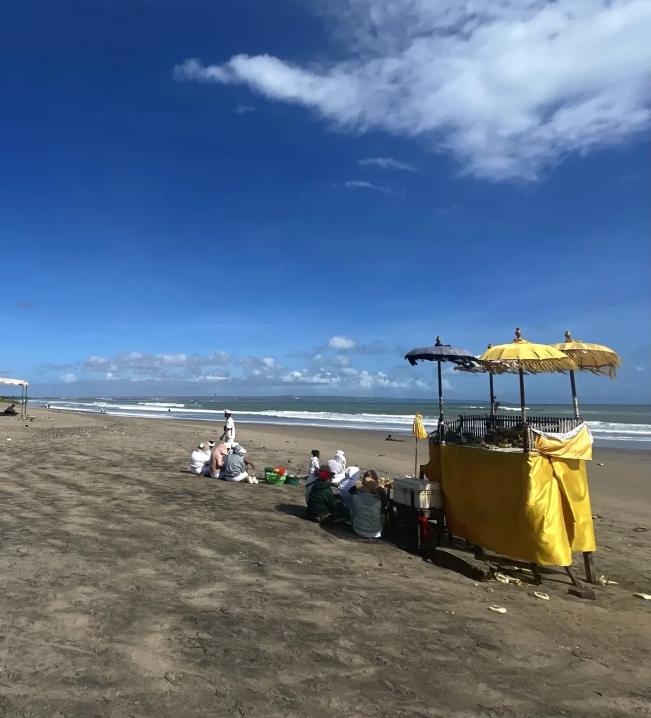 People sitting on beach near a yellow stand