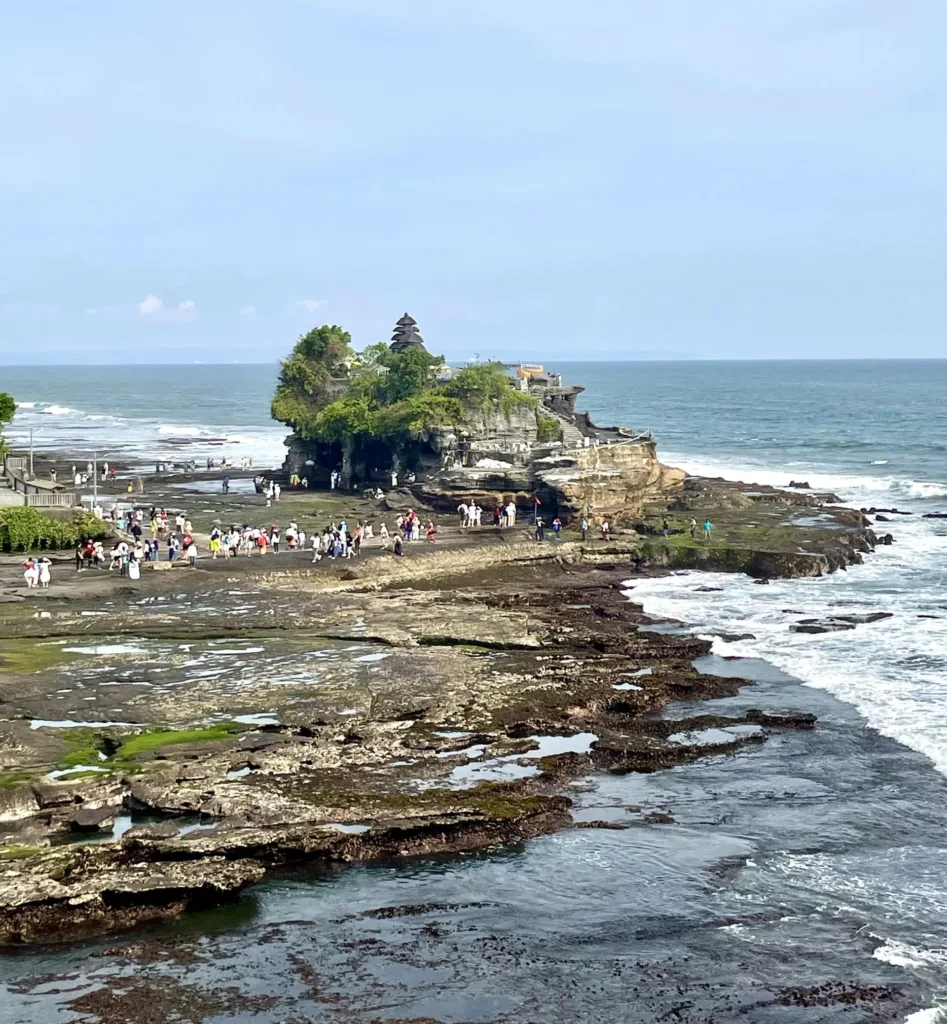 Crowds near a temple situated on rocky surface by the sea