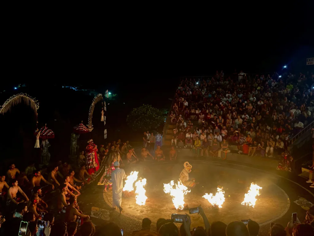 Ringed performance with fire and dancers with crowds around ring