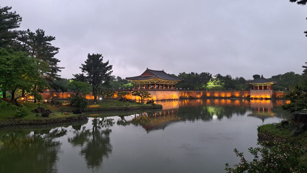 A lit palace by a lake surrounded by trees