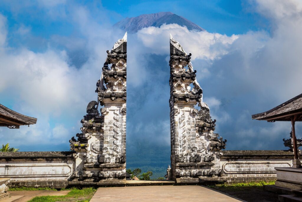 Temple entrance in grey stones with clouds and mountains in the back.