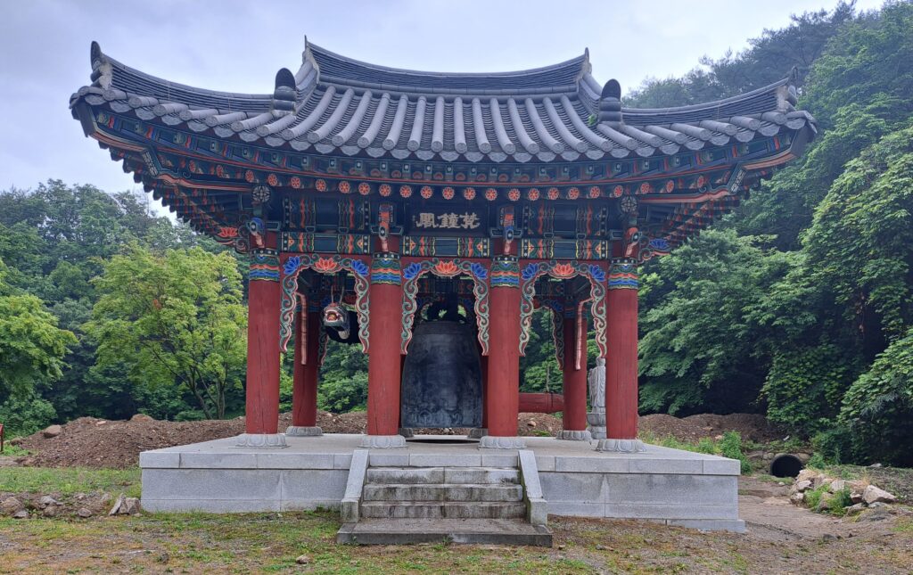 A large black bell standing in the middle of a temple