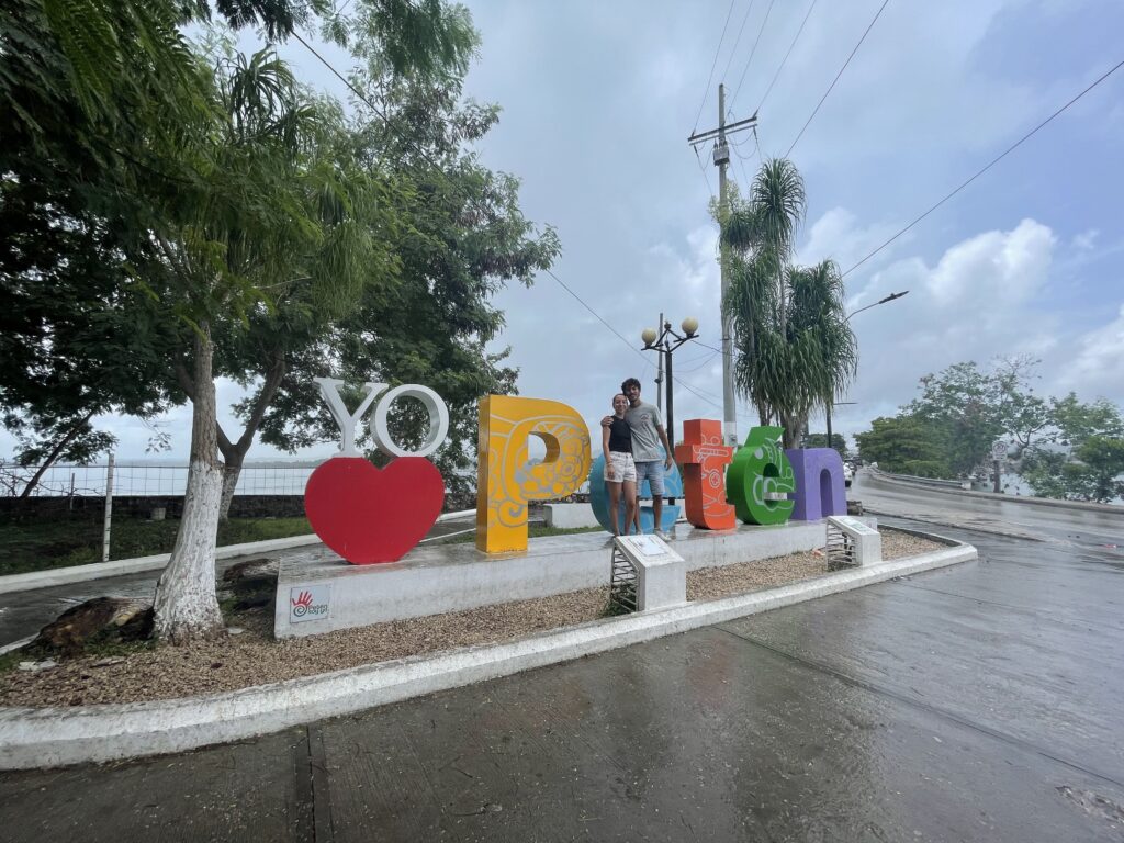 A man a woman standing in front of sign that spells Peten