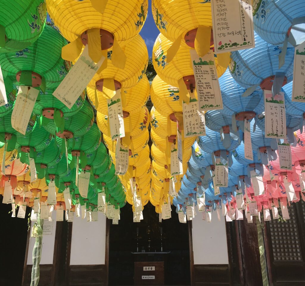 Green, yellow, blue, and pink lanterns hanging in front of a temple